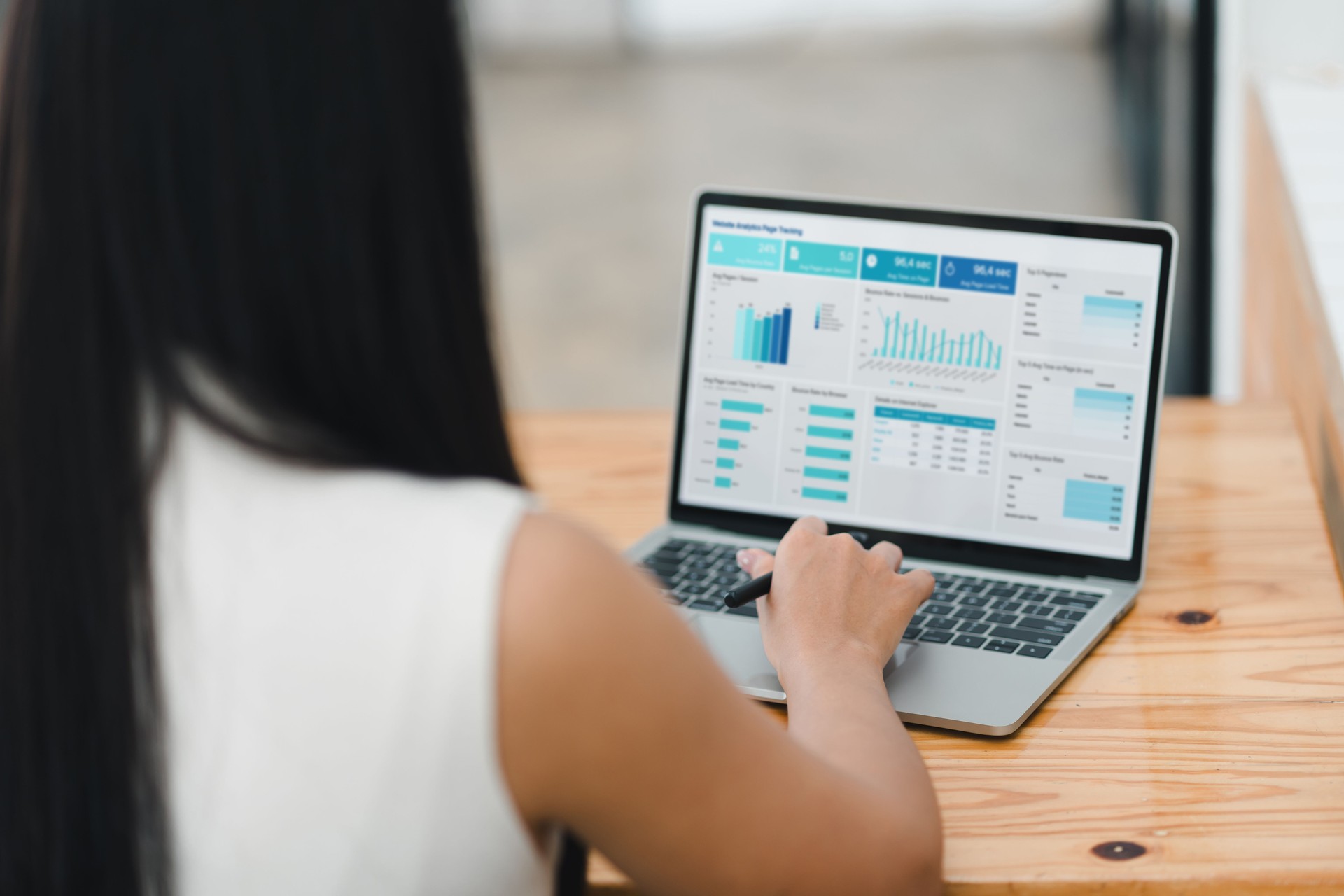 person analyzing data on laptop, focusing on various charts and graphs displayed on screen. setting suggests modern workspace, emphasizing productivity and technology